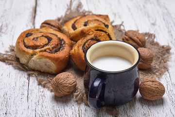 Wall Mural - Basket of homemade buns with jam, served on old wooden table with walnuts and cup of milk