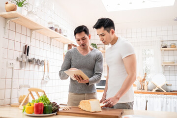 LGBT, happy Asian gay couple cooking food together in kitchen.