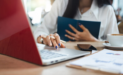 Close-up of hand businesswoman using computer laptop and smart phone working with paperwork of investment on desk