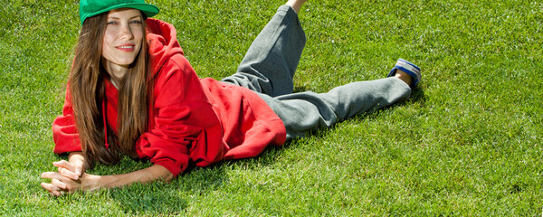 Wall Mural - young woman lying on the grass wearing color youth clothes, space