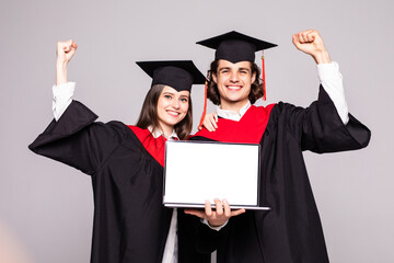 Wall Mural - Young graduation couple holding laptop on white background