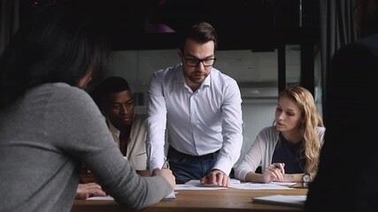 Wall Mural - Serious male corporate leader boss analyze financial report data training workers team at briefing table, businessman ceo explaining work plan paperwork to diverse employees group at company meeting