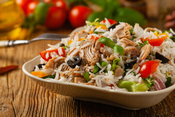 Wall Mural - Italian tuna salad with rice, olives and capers. Front view. Natural wooden background.