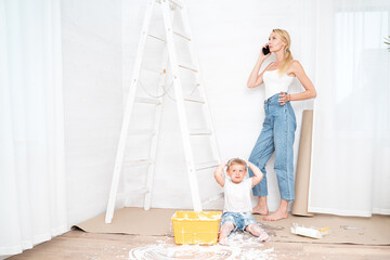 Mother with son painting the wall in home.