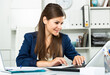 © JackF - Smiling woman working with papers and laptop in office. High quality photo
