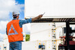 © totojang1977 - Confident Caucasian man engineer wearing white safety helmet using walkies talkie call to driver and check for control loading containers box from Cargo freight ship for import and export, transport