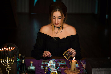   Woman fortune teller on a Tarot cards, Concept of predictions, magical rituals and wicca elements on a table 