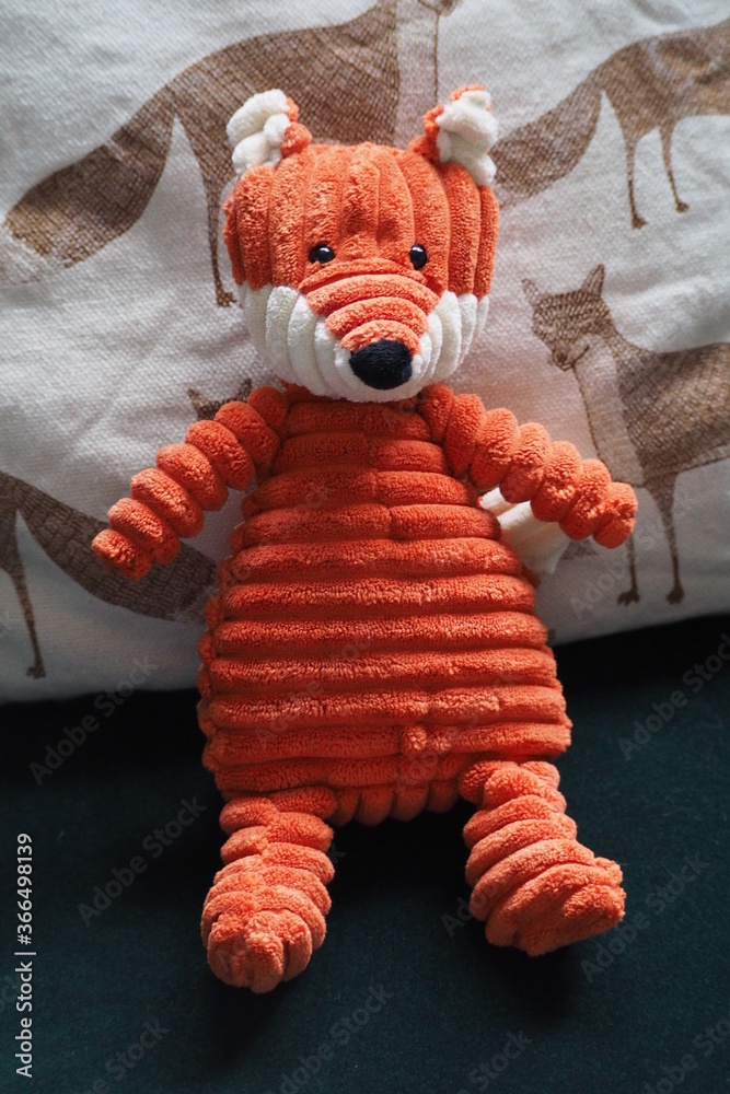  Rudy lis, dziecięca zabawka na tle poduszki we wzory lisków - obrazy, fototapety, plakaty 