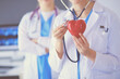 © lenets_tan - Cropped shoot of two young doctors female with stethoscope holding heart.