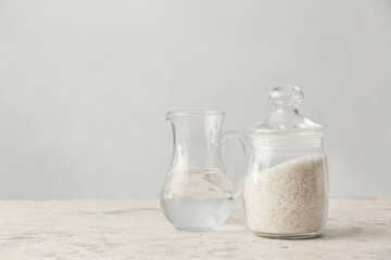 Jar with rice and jug of water on table