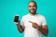 © fotofabrika - Smiling african american man pointing his finger on smartphone screen