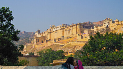 Breathtaking architecture details and panoramic scenic building view of Amber Fort and Palace during morning hours in yellow and orange light near Jaipur in Rajasthan in India with historic walls