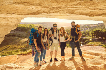 Wall Mural - groups of tourists with backpacks in a cave in the mountains look at the camera together.