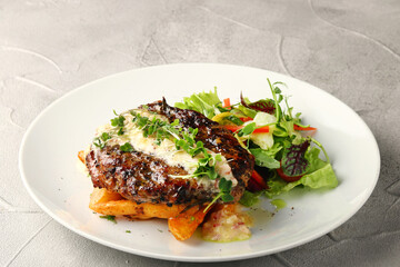 grilled beef with potato and salad closeup on white plate and concrete background