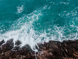 Wall Mural - aerial view of crashing waves on rocks.