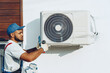 © fotofabrika - Repairman in uniform installing the outside unit of air conditioner