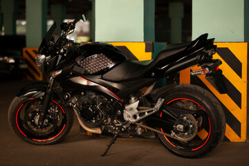 Wall Mural - Black motorcycle on the background of underground parking.