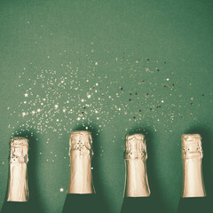 Bottles of champagne with gold glitter and space for text on green background