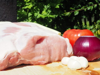 pork loin on the bone with garlic and vegetables on a wooden Board. cooking in nature. meat