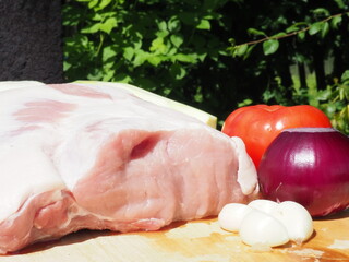 pork loin on the bone with garlic and vegetables on a wooden Board. cooking in nature. meat