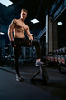 © serhiibobyk - Shirtless bodybuilder posing in gym.