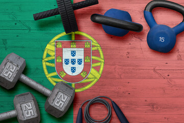 Portugal sports club concept. Top view of heavy weight plates with iron bar on national background.