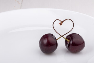 sweet cherries with heart shaped stems on a plate