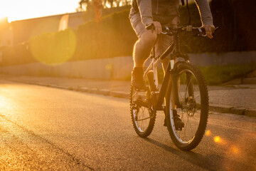 Man riding a bicycle with a sunset background.