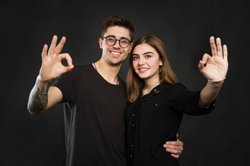 Couple making OK sign on black background