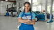 © Svitlana - Top service is my motive. Portrait of young african american woman, professional female mechanic in uniform smiling at camera, standing in auto repair shop. Car service, repair, maintenance concept