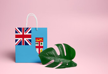 Fiji shopping concept. National cardboard shopping bag with monstera leaf and pink background. Online shopping theme.