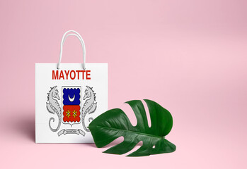 Mayotte shopping concept. National cardboard shopping bag with monstera leaf and pink background. Online shopping theme.