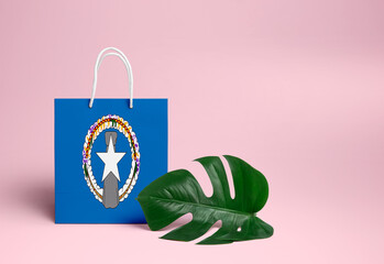 Northern Mariana Islands shopping concept. National cardboard shopping bag with monstera leaf and pink background. Online shopping theme.