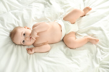 Poster - Cute little baby in diaper lying on bed, above view