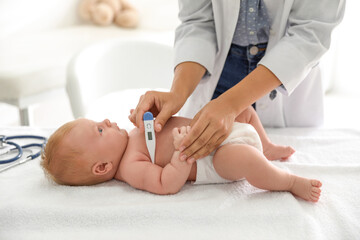 Poster - Doctor measuring temperature of little baby with digital thermometer indoors, closeup. Health care