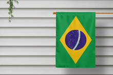 Brazil National Small Flag Hangs From A Picket Fence Along The Wooden Wall In A Rural Town. Independence Day Concept.