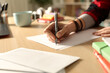 © PheelingsMedia - Student hand writing letter at home in the night