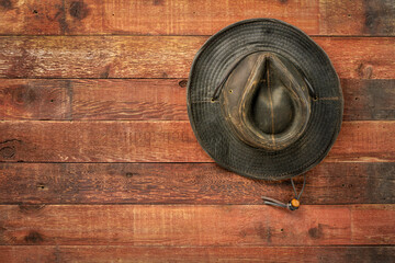 Sticker - weathered outback oilskin hat hanging on rustic red barn wooden wall with a copy space