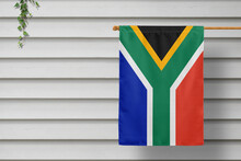 South Africa National Small Flag Hangs From A Picket Fence Along The Wooden Wall In A Rural Town. Independence Day Concept.