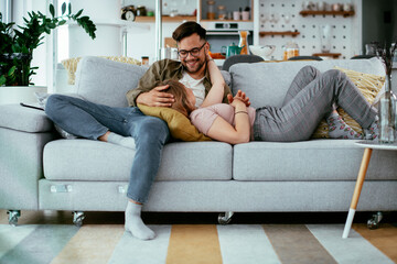 Wall Mural - Husband and wife enjoying on sofa. Happy couple relaxing in living room.	