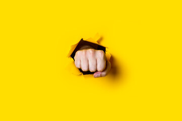 Male fist, hand with clenched fingers on a yellow background. Round stone.