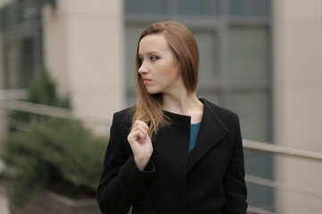 Wall Mural - The girl in black coat. Beautiful emotional young girl in the city. Shawl or handkerchief on a person. 