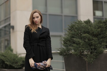 Wall Mural - The girl in black coat. Beautiful emotional young girl in the city. Shawl or handkerchief on a person. 