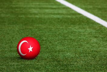 Turkey flag on ball at soccer field background. National football theme on green grass. Sports competition concept.