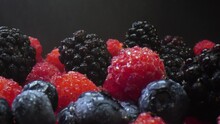 Blackberries, Blueberries And Raspberries Sprinkled With Water On A Black Background. Composition Of A Raw And Fresh Forest Fruits Close Up.