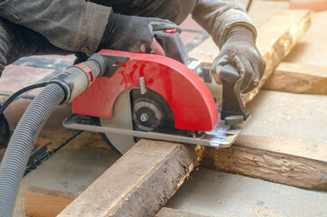 Canvas Print - Carpenter cuts wooden board with hand-held circular saw