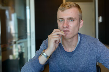 Wall Mural - Portrait of young man with blond hair relaxing at home