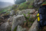 Fototapeta  - plecak turystyczny i żółta metalowa butelka na wodę na tle zamglonego górskiego szlaku