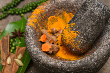 Wall Mural - turmeric roots and powder in a mortar Kerala South India. Traditional Indian kitchen using vintage grinder for powdering spices which is used widely in curry and antiseptic Ayurveda treatments  