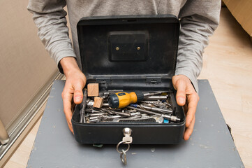 Close up. Home renovation tool kit. Male hands are holding an open toolbox.